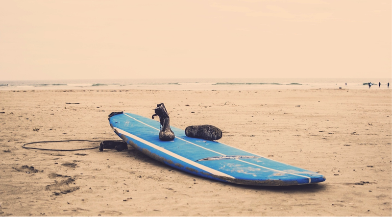 Surfboard and boots on beach